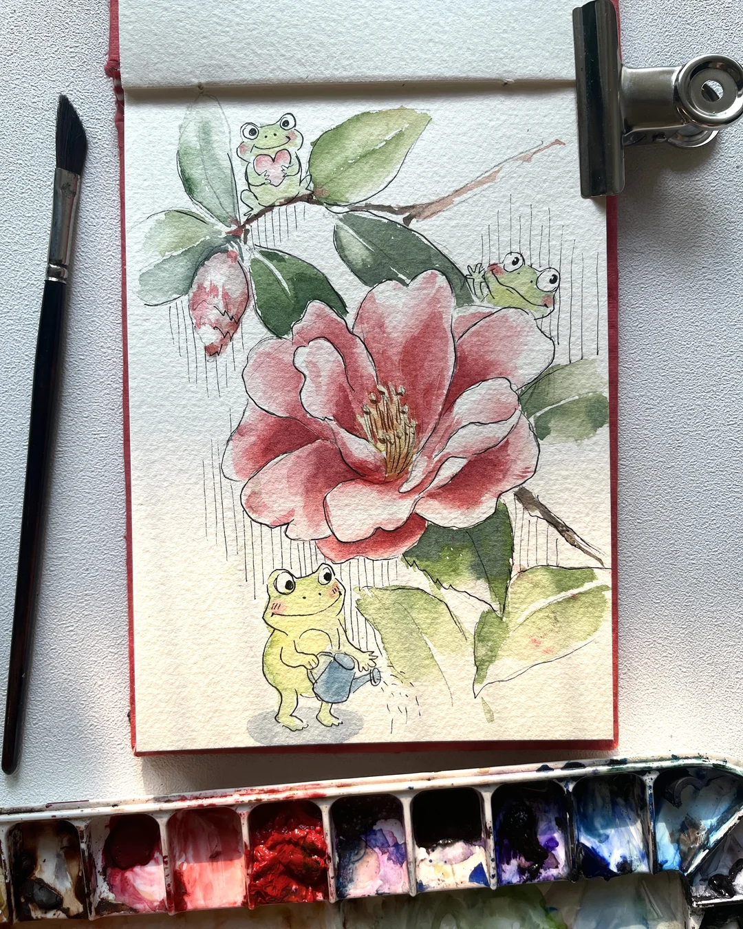A camellia in watercolour and pen, with three frog doodles